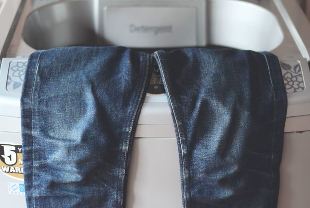 Soak the jeans in hot water and then dry them in the dryer